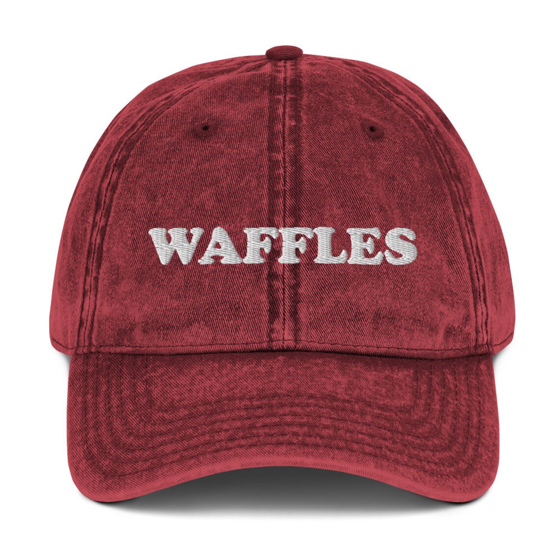Washed out red denim dad hat for waffle lovers - The Waffles Dad Hat! This funny food dad hat is the perfect everyday accessory to show off your love of waffles. Wear the unique foodie dad hat for any occasion or give it as a stylish weird gift for a waffle lover. Show off your love of waffles and favorite foods in our vintage style weird dad hats and clothing.