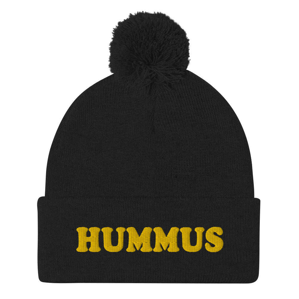 Black Beanie with Hummus Embroidered on the front in yellow - Do you love hummus? Looking for a funny gift for a foodie? This warm and cozy, embroidered beanie is just what you need. It's a classic pom pom beanie with "HUMMUS", embroidered on the front. The perfect funny beanie for hummus lovers and foodies of all kinds. Celebrate your favorite foods in our funky foodie apparel. 