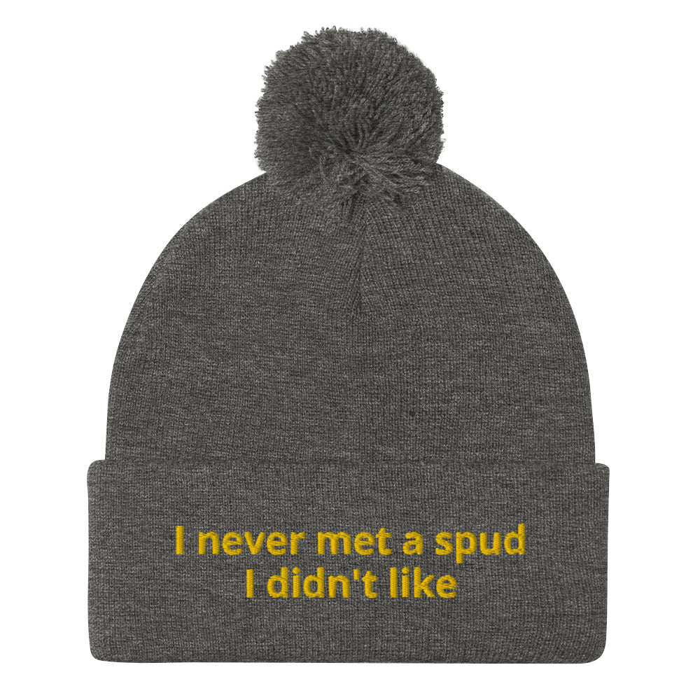 Gray I Never Met A Spud I Didn't Like Dolly Beanie - Do you love potatoes? Looking for a funny gift for a potato enthusiast? This warm and cozy, embroidered beanie is just what you need. It's a classic pom pom beanie with "I never met a spud I didn't like", expertly embroidered on the front. The perfect funny beanie for everyday foodies and potato lovers of all kinds.