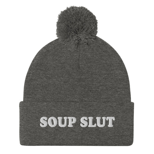 Gray Embroidered Beanie with Soup Slut from Nina's Funky Shop - Love soup? Looking for a funny gift for a soup enthusiast? This warm and cozy, embroidered beanie is just what you need. It's a classic pom pom beanie with "soup slut", expertly embroidered on the front. The perfect weird beanie hat for soup sluts and foodies of all kinds. Celebrate your favorite foods in our funky foodie apparel. 