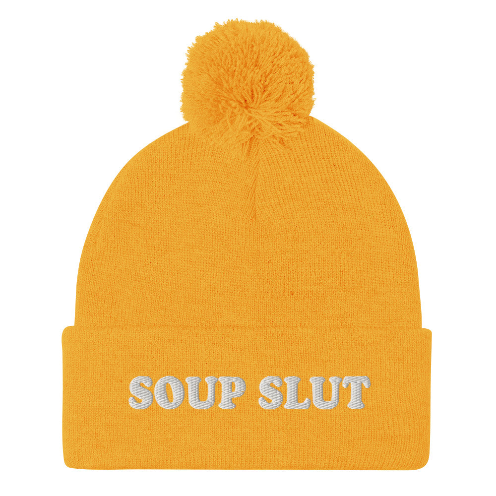 Yellow Embroidered Beanie with Soup Slut from Nina's Funky Shop - Love soup? Looking for a funny gift for a soup enthusiast? This warm and cozy, embroidered beanie is just what you need. It's a classic pom pom beanie with "soup slut", expertly embroidered on the front. The perfect weird beanie hat for soup sluts and foodies of all kinds. Celebrate your favorite foods in our funky foodie apparel.