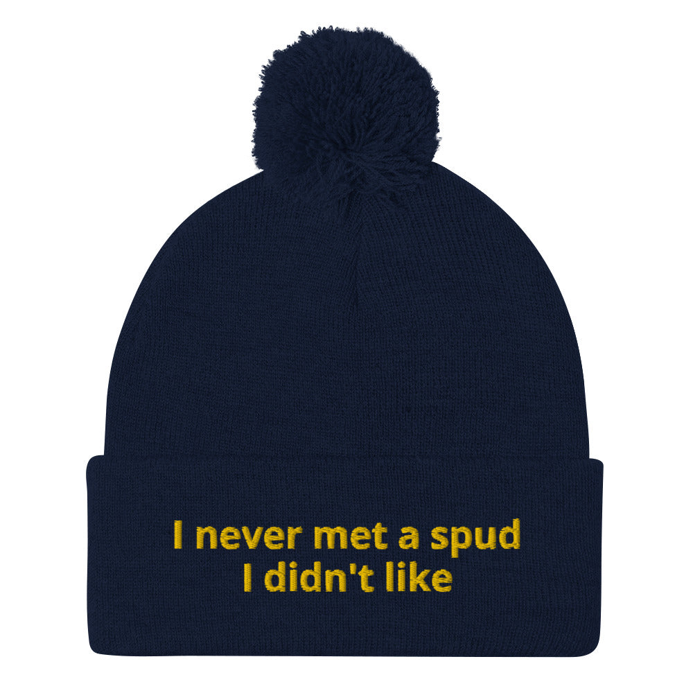 Navy I Never Met A Spud I Didn't Like Dolly Beanie - Do you love potatoes? Looking for a funny gift for a potato enthusiast? This warm and cozy, embroidered beanie is just what you need. It's a classic pom pom beanie with "I never met a spud I didn't like", expertly embroidered on the front. The perfect funny beanie for everyday foodies and potato lovers of all kinds.