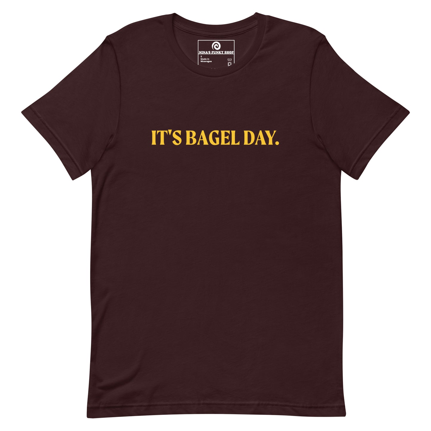 Oxblood Black It's Bagel Day T-Shirt - Are you a bagel enthusiast? Looking for a funny gift for a fellow bagel lover? Every day is bagel day in our "It's Bagel Day T-shirt". It's a soft and comfortable, unisex t-shirt that comes in a variety of colors with a funny bagel saying, expertly printed on the front. Eat your favorite bagels and make a statement. Celebrate your favorite foods in our funky foodie apparel.