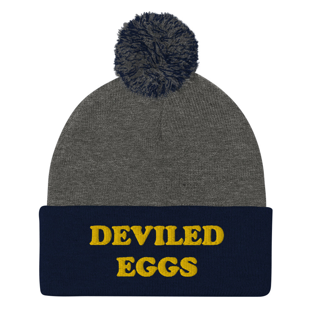 Deviled Eggs Pom-Pom Beanie. This funky foodie beanie is a warm and cozy hat for cold weather. It's a classic beanie with a pom pom and a unique deviled egg lover embroidery. This funny beanie is unique and weird and a perfect funny hat for a unique gift idea. Ideal for foodies who love deviled eggs and weird hats.